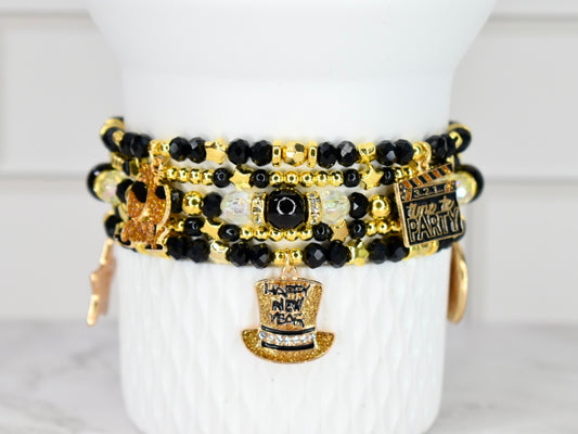 Stack of black, gold, and white beaded bracelets on a white surface