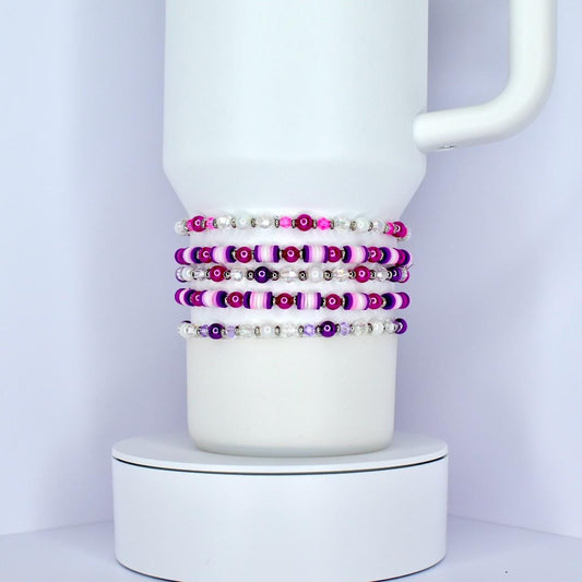 Set of beaded bracelets on a white mug against a light purple background