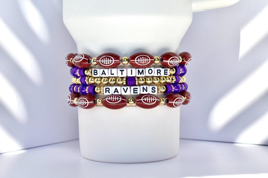 Stack of Baltimore Ravens-themed bracelets on a white tumbler with a white background