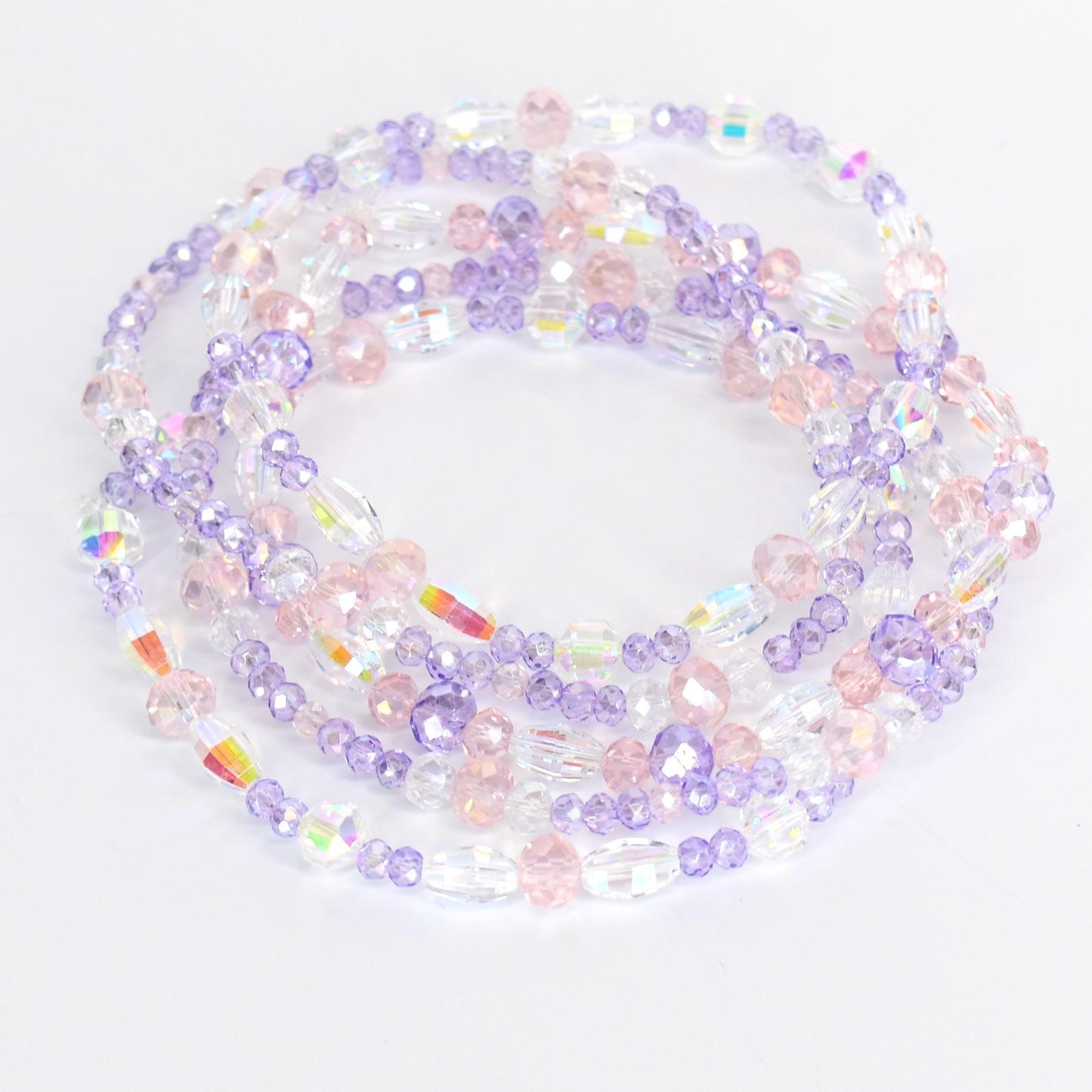 Strands of beaded jewelry in shades of clear, pink, and lavender. The beads are various shapes and sizes, including round and oval. The jewelry is arranged in a circular pattern, with the beads reflecting light.