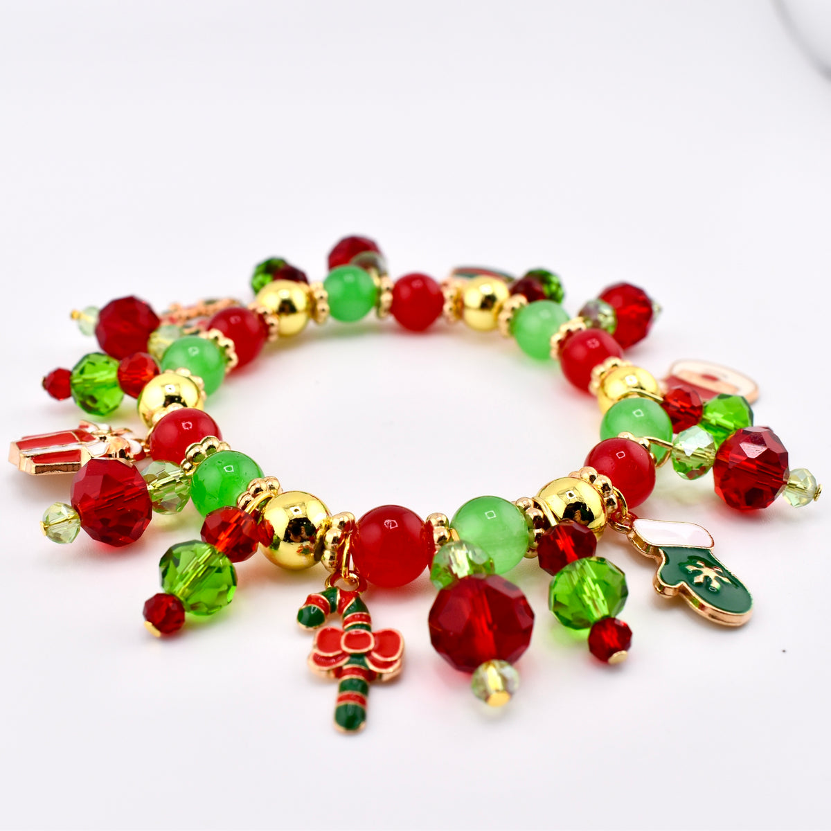 Red, green, gold beaded bracelets on a red Stanley with a white background.