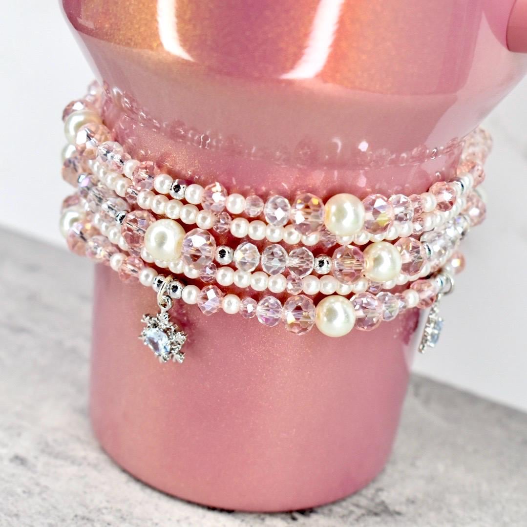 Stack of pearl and beaded bracelets on a pink cup