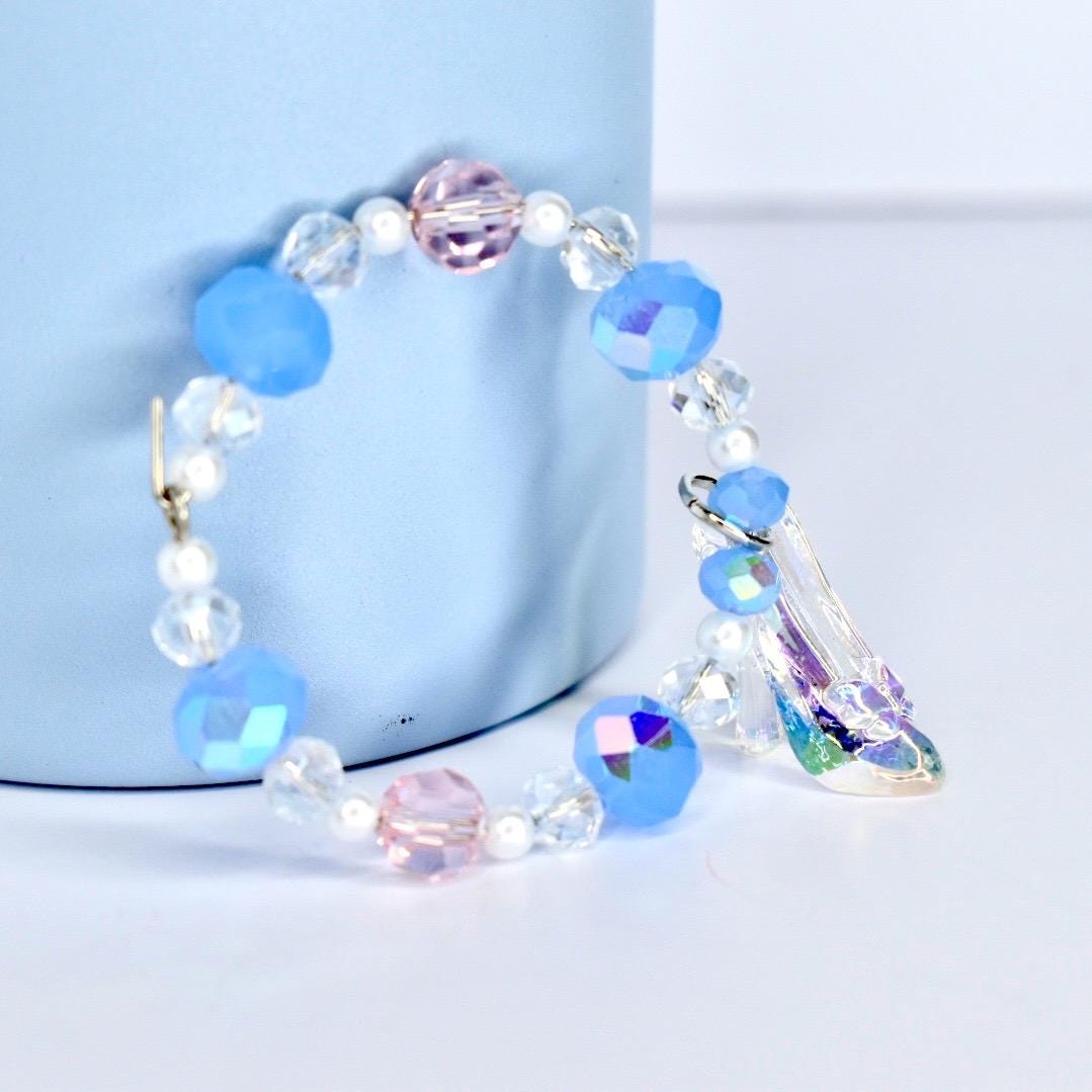 Beaded bracelet with blue and clear beads  and a glass slipper on a light blue background with a light blue stanley
