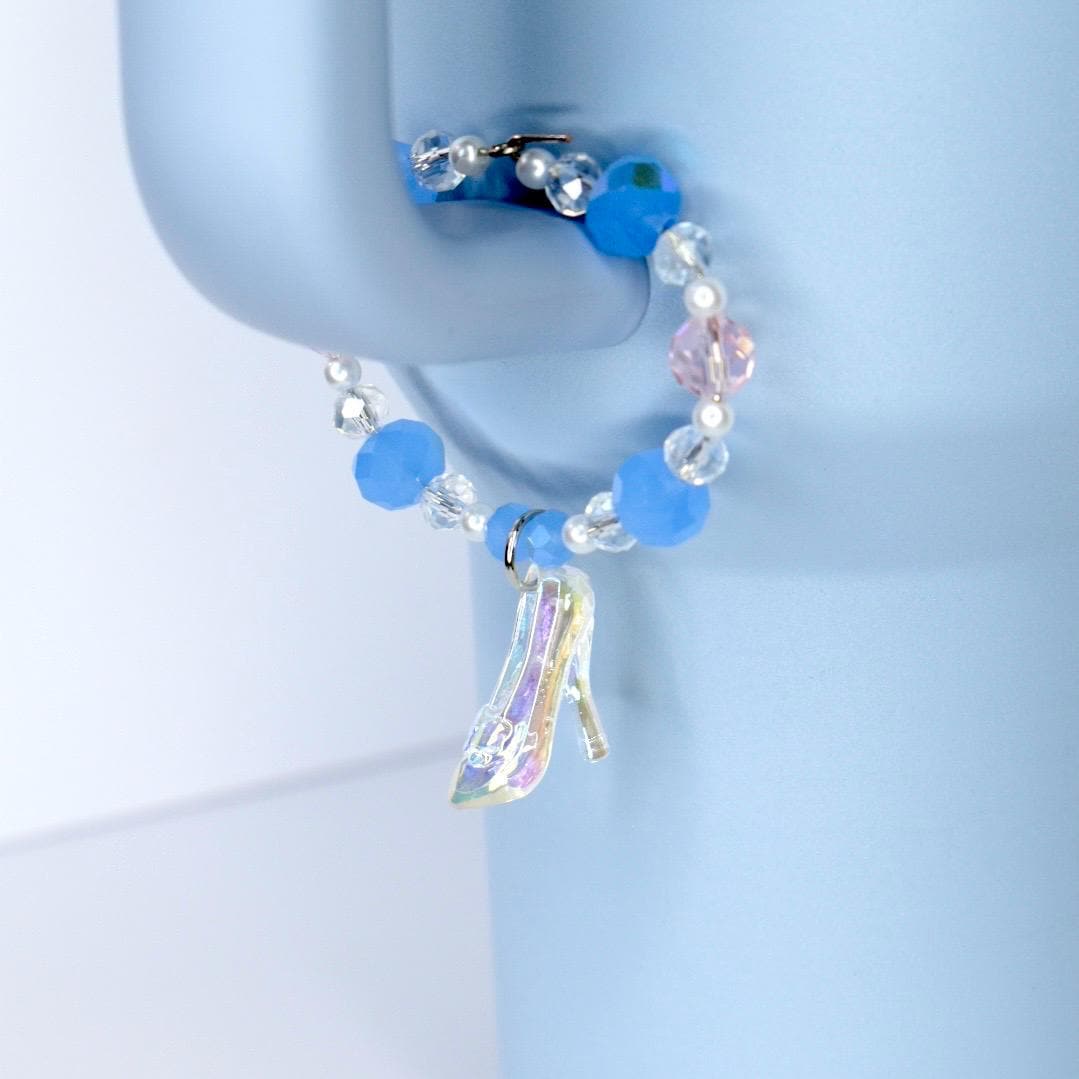 Blue beaded tumbler charm with a high-heeled shoe charm on a light blue background