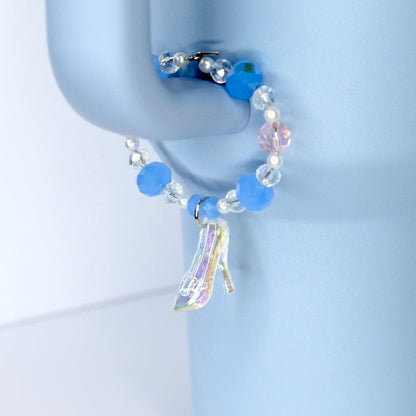 Blue beaded tumbler charm with a high-heeled shoe charm on a light blue background