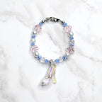 Bracelet with pastel-colored beads and a glass slipper charm on a white marble background
