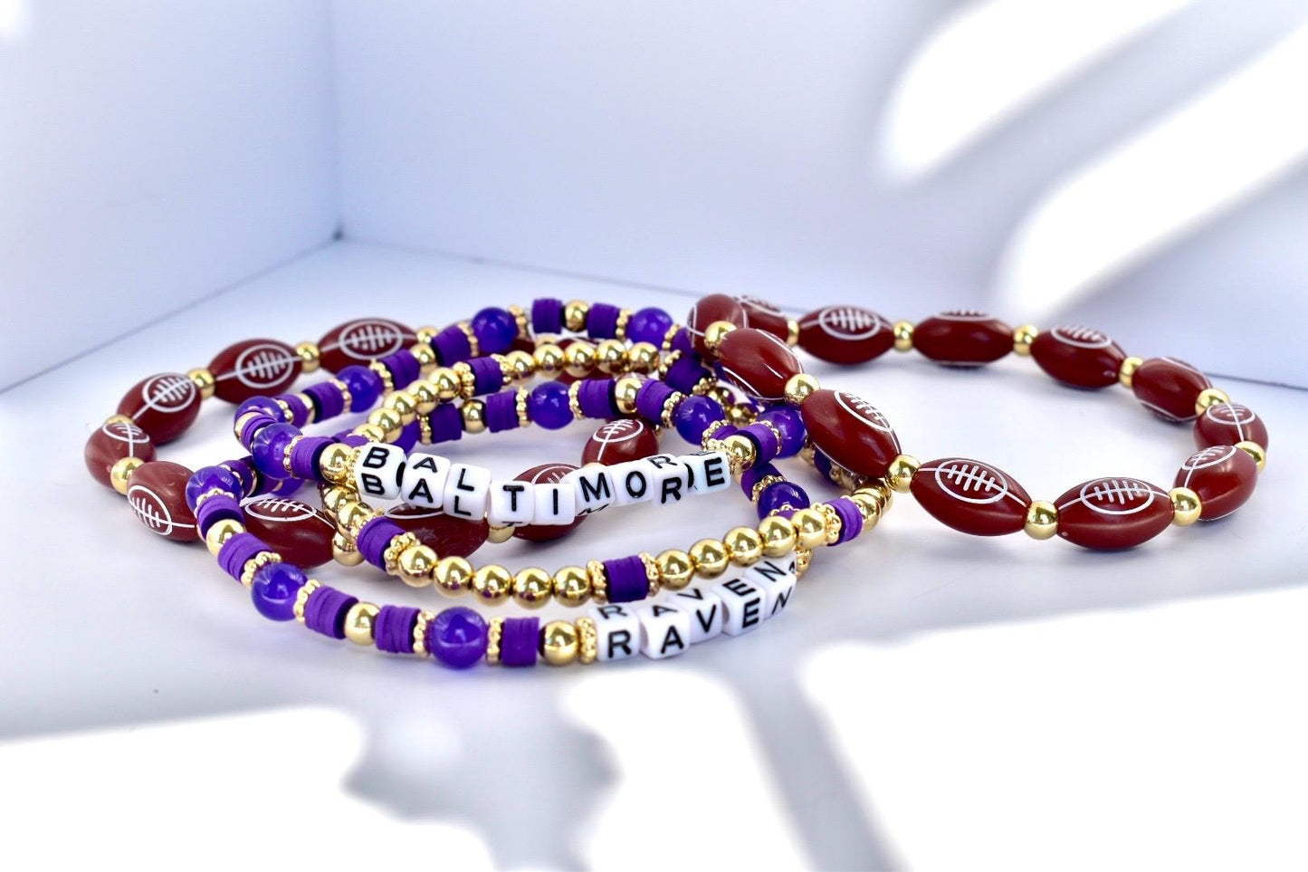 Set of bracelets with football beads and 'Baltimore Ravens' text on a white background