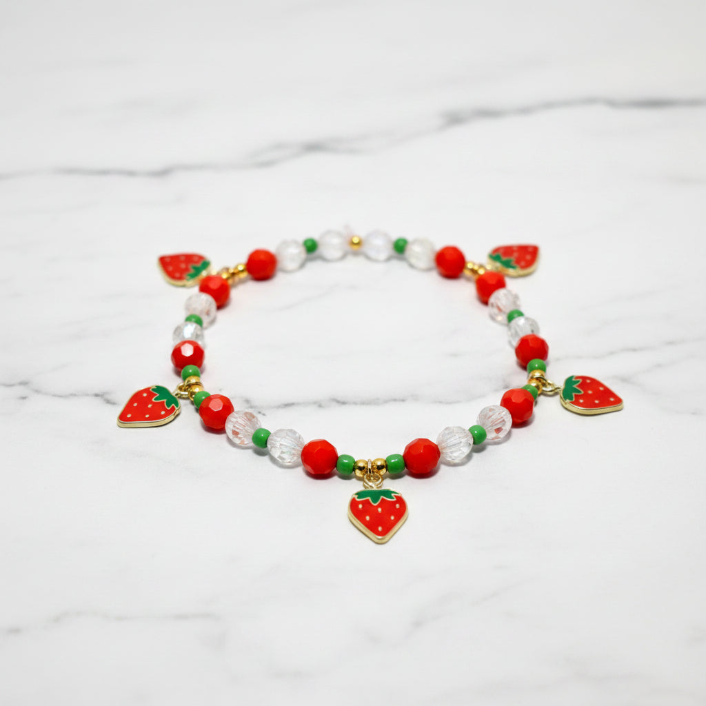 A red and green beaded bracelet with strawberry charms. The bracelet has a white background with the text Design Name: Berry Sweetheart.