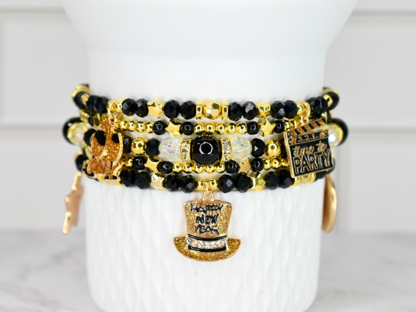Stack of black, gold, and white beaded bracelets on a white surface