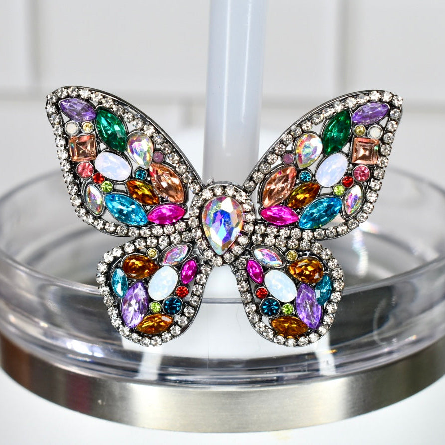 Butterfly-shaped straw charm with colorful gemstones on a white background