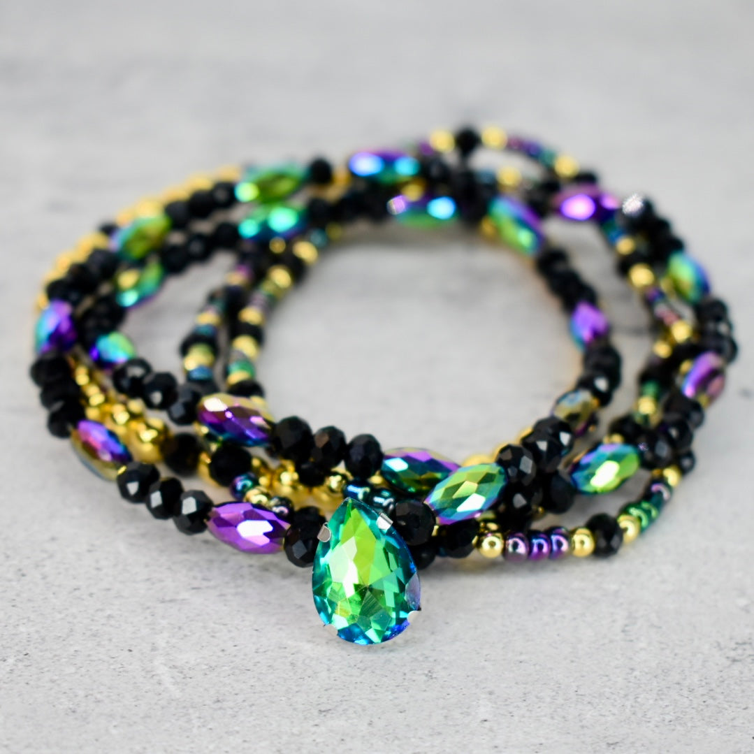Multicolored beaded bracelet with a large central gemstone on a light gray background