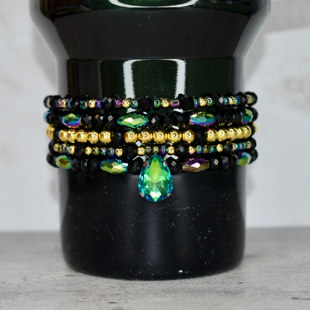 Stack of beaded bracelets with a teardrop gemstone on a Elphaba for Good Stanley.