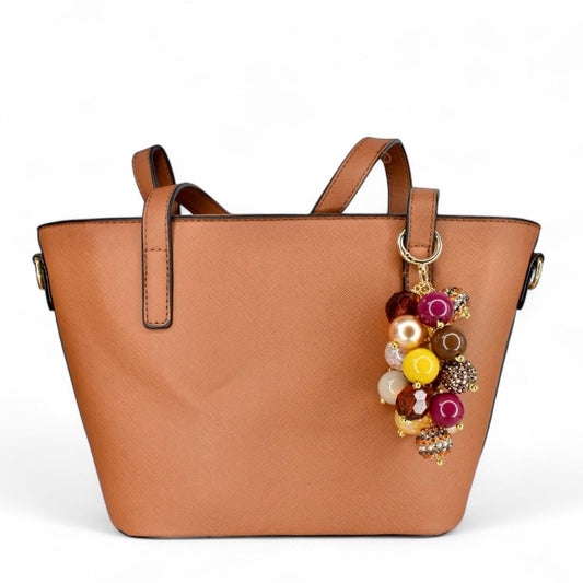 Brown handbag with a colorful fall keychain on a white background
