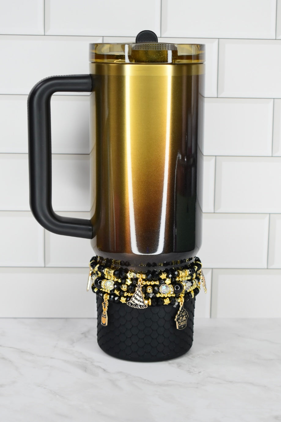 Gold and black insulated mug with decorative elements on a white surface.