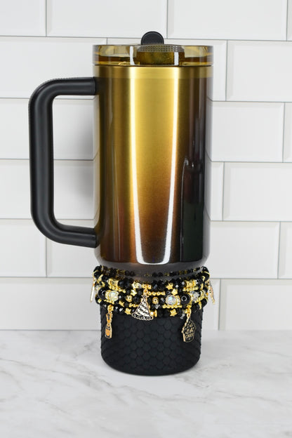 Gold and black insulated mug with decorative elements on a white surface.