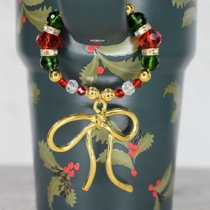 Holiday botanical Stanley with handle charm that has red green and gold beads with a gold bow charm and magnetic clasp