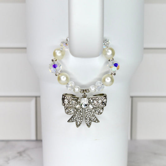 Pearl tumbler handle bracelet with pearls and a decorative bow on a white Stanley against a white background