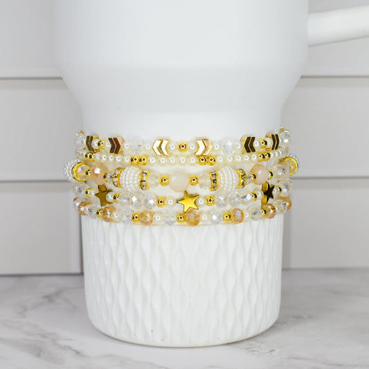 Pearl crystal and gold bracelet stack on a white stanley tumbler.