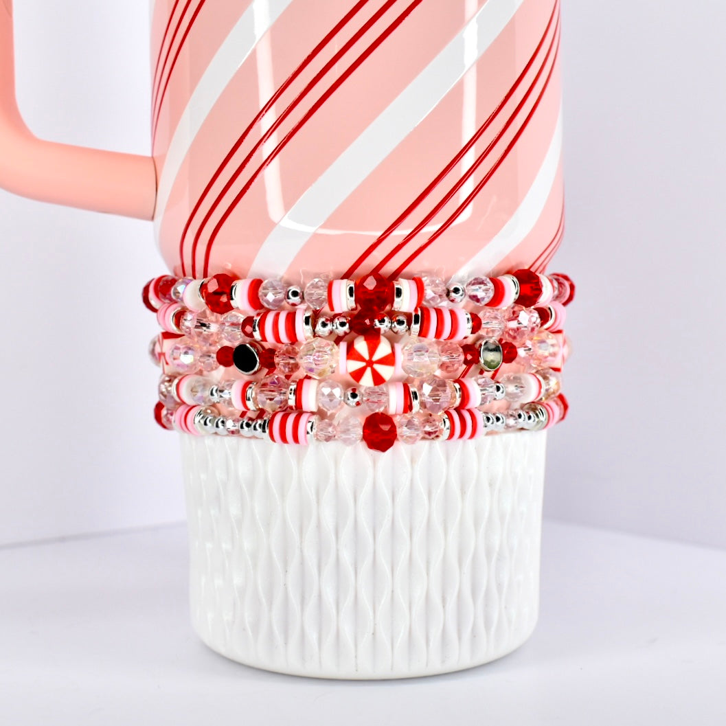Set of red and white beaded bracelets on a striped mug with a white background