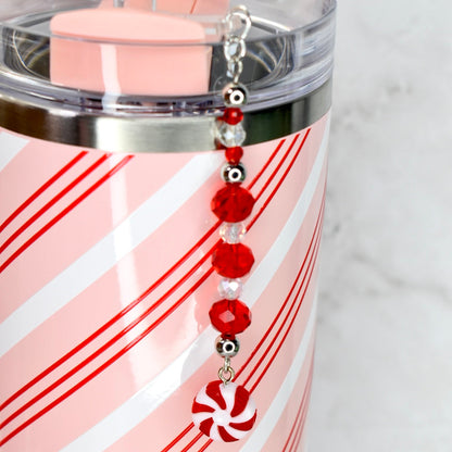 Pink tumbler with red stripes and a peppermint candy charm .