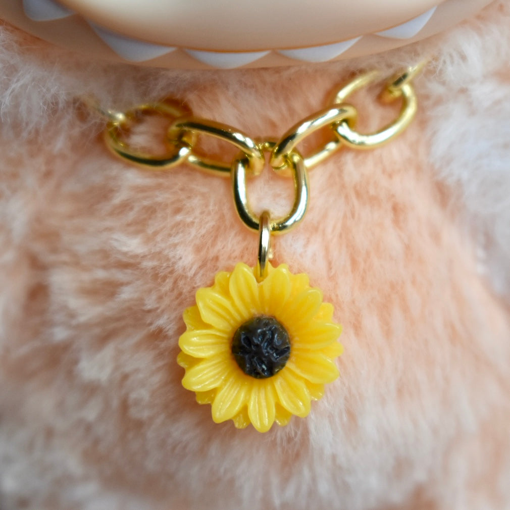 Gold chain with a yellow sunflower charm on a orange Labubu