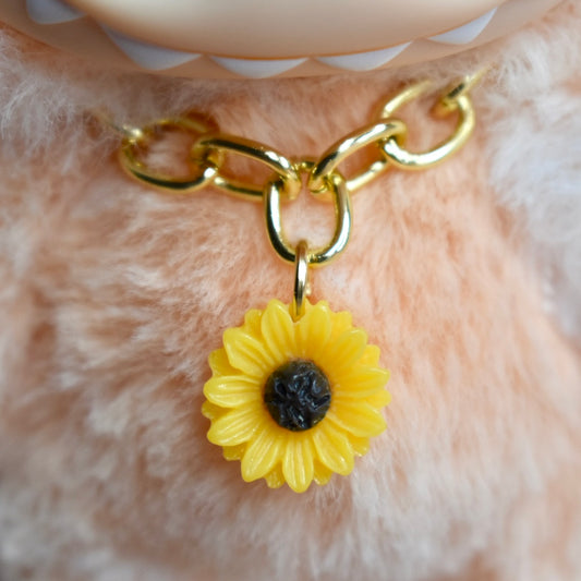 Gold chain with a yellow sunflower charm on a orange Labubu