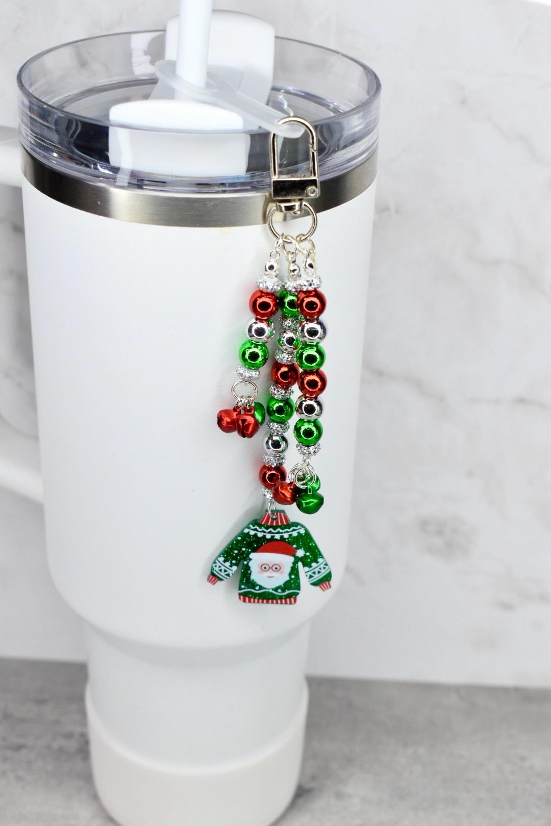 Tumbler with a festive keychain featuring a green ugly sweater design on a white background