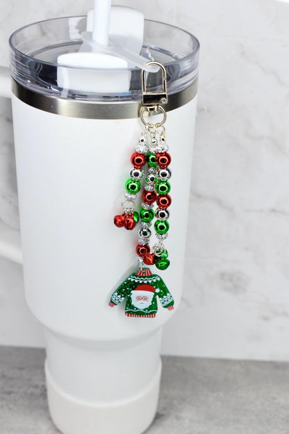 Tumbler with a festive keychain featuring a green ugly sweater design on a white background