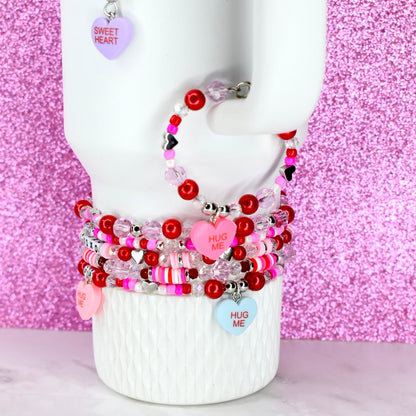 Stack of colorful beaded bracelets on a mannequin arm against a pink glittery background