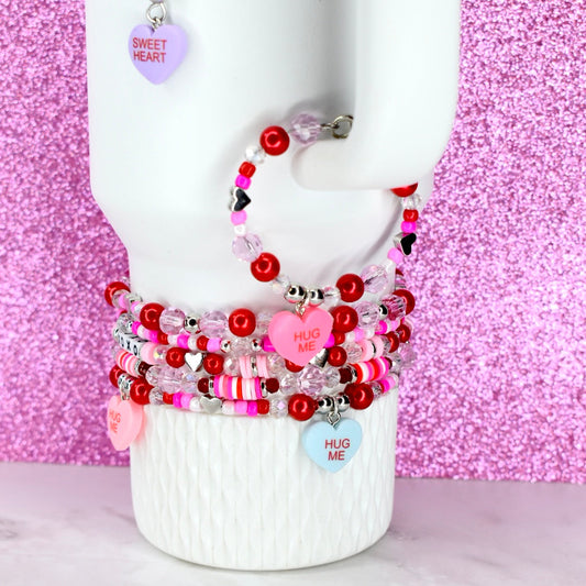Stack of colorful beaded bracelets on a mannequin arm against a pink glittery background