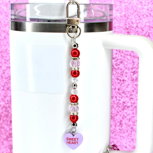 Tumbler with a beaded straw charm on a pink background