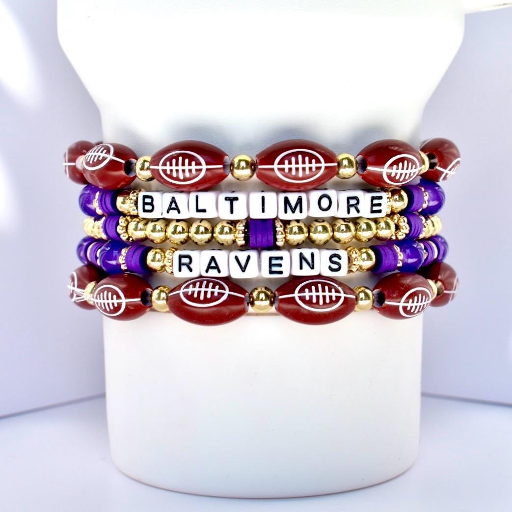 Stack of Baltimore Ravens-themed beaded bracelets on a white Stanley with a white background.
