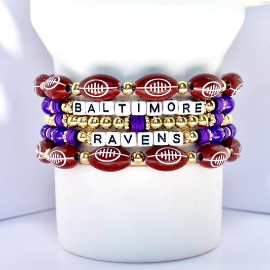Stack of Baltimore Ravens-themed beaded bracelets on a white Stanley with a white background.