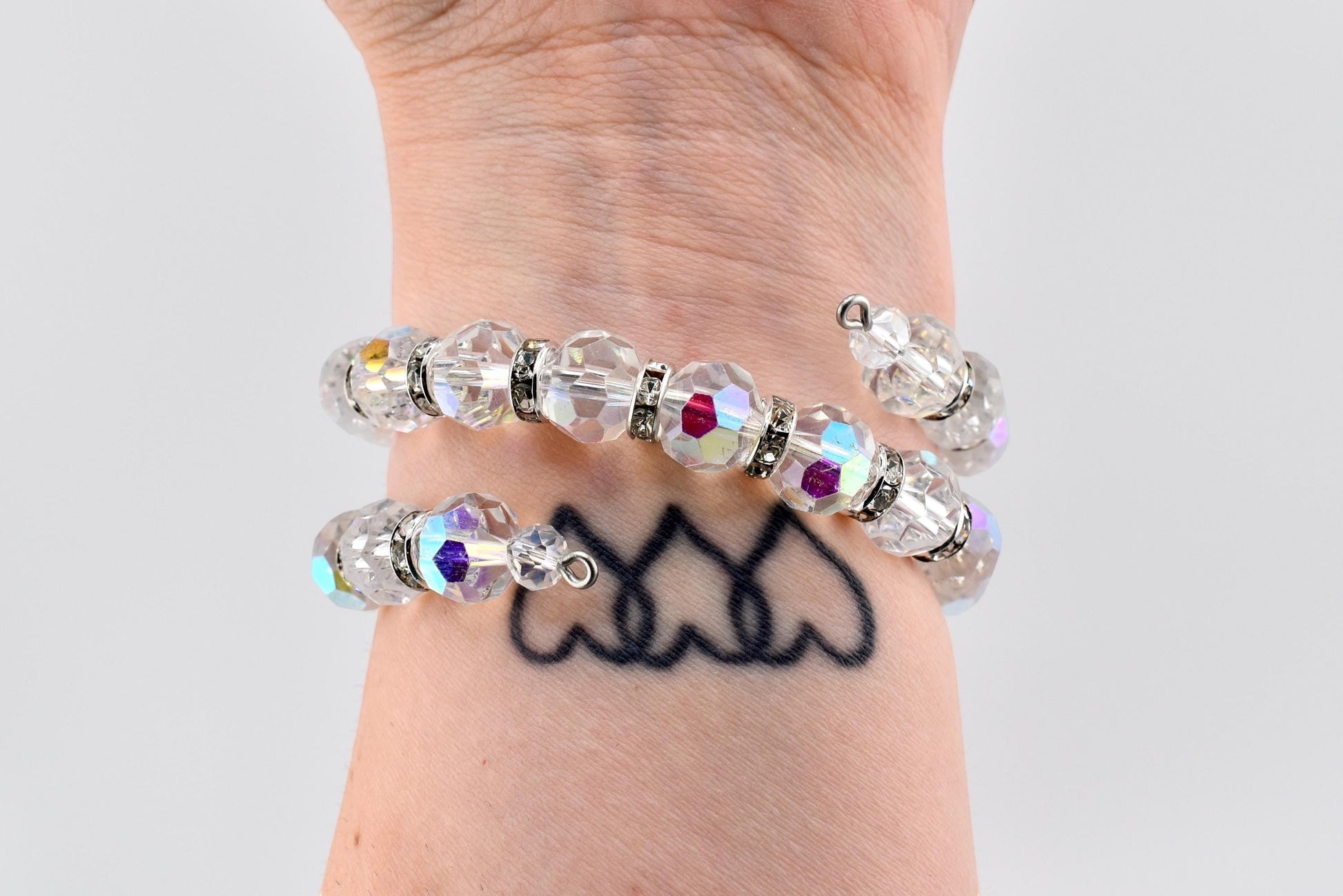 Calathea Collective iridescent crystal wrap bracelet with rhinestone spacers on wrist. Features faceted AB finish crystals and silver-tone spacers.