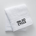 Calathea Collective white terry cloth sweat towel with black "OH-SO CYCLE" logo, perfect for indoor cycling classes.