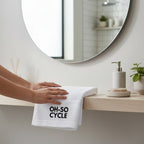 Calathea Collective white cotton sweat towel with black "OH-SO CYCLE" logo, perfect for indoor cycling classes.