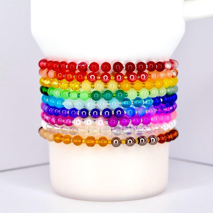 Set of rainbow-colored beaded bracelets on a white Stanley tumbler