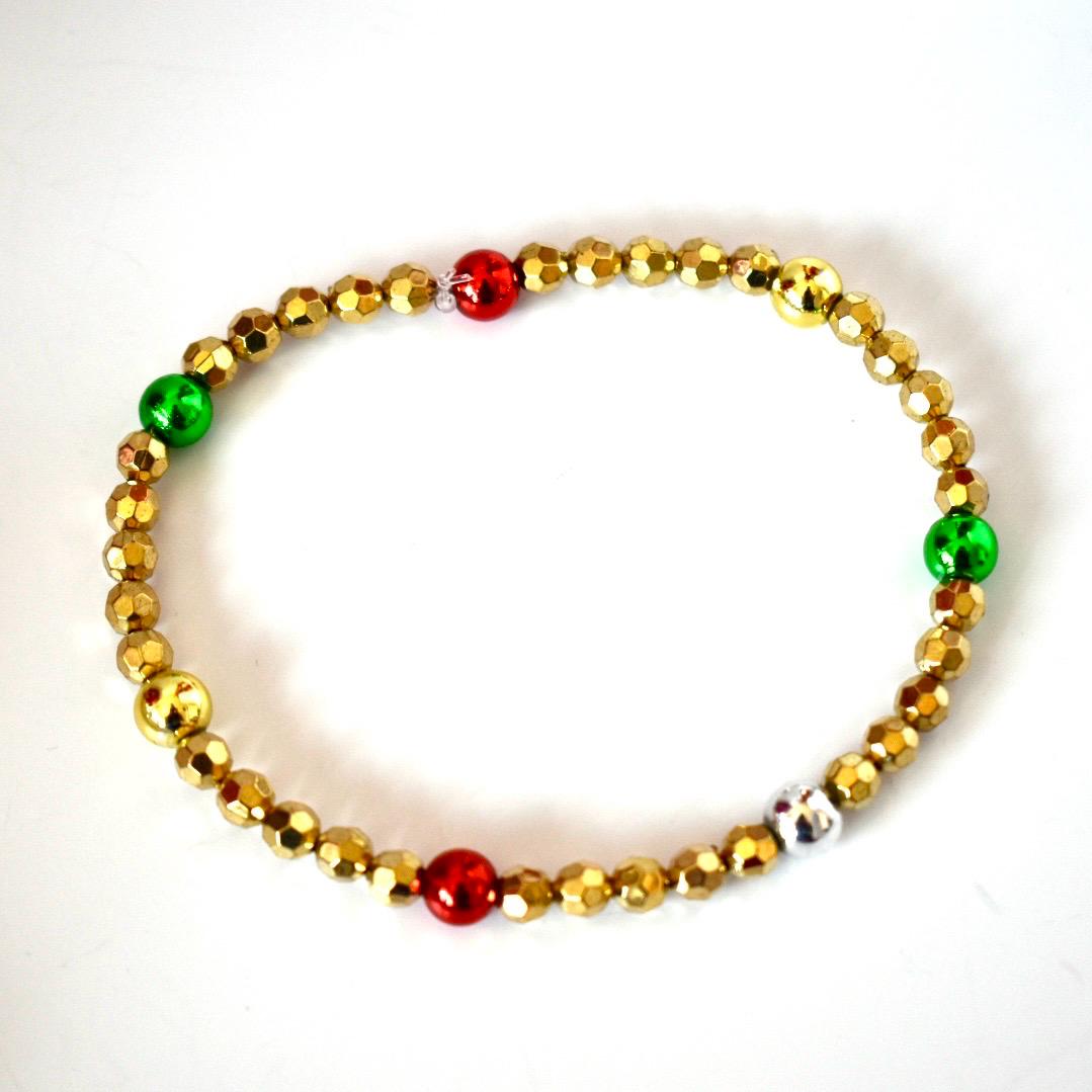 Beaded bracelet with gold, red, and green beads on a white background