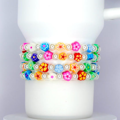 Bright colorful flower and pearl tumbler bracelet set with multicolor floral beads and white pearls, wrapped around a white tumbler.