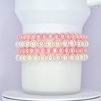 A white Stanley tumbler wrapped with a classic and elegant bracelet stack made of alternating rows of glossy pink and white pearl beads. The bracelets are styled as Stanley cup accessories with a soft and feminine touch.