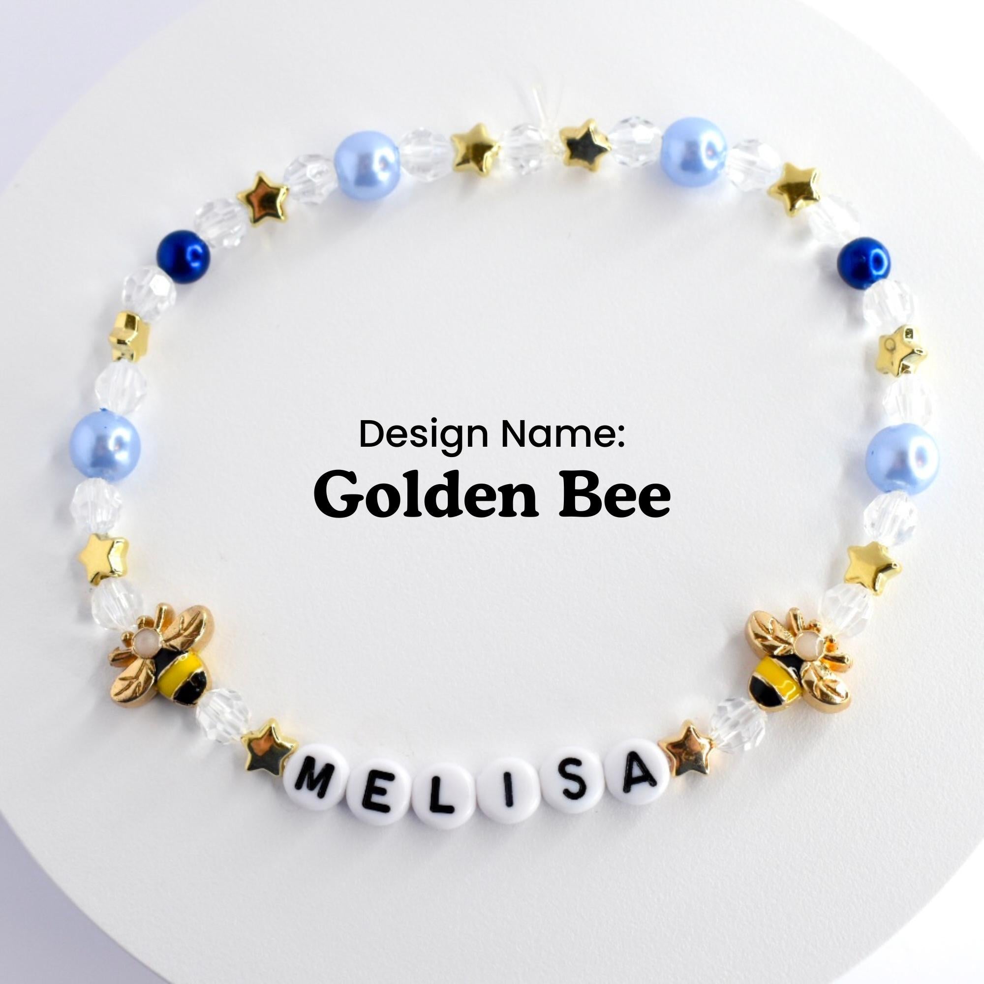 A blue and gold beaded bracelet with two bee charms and the name 'MELISA' spelled out in white beads. The bracelet has a design name of 'Golden Bee'.