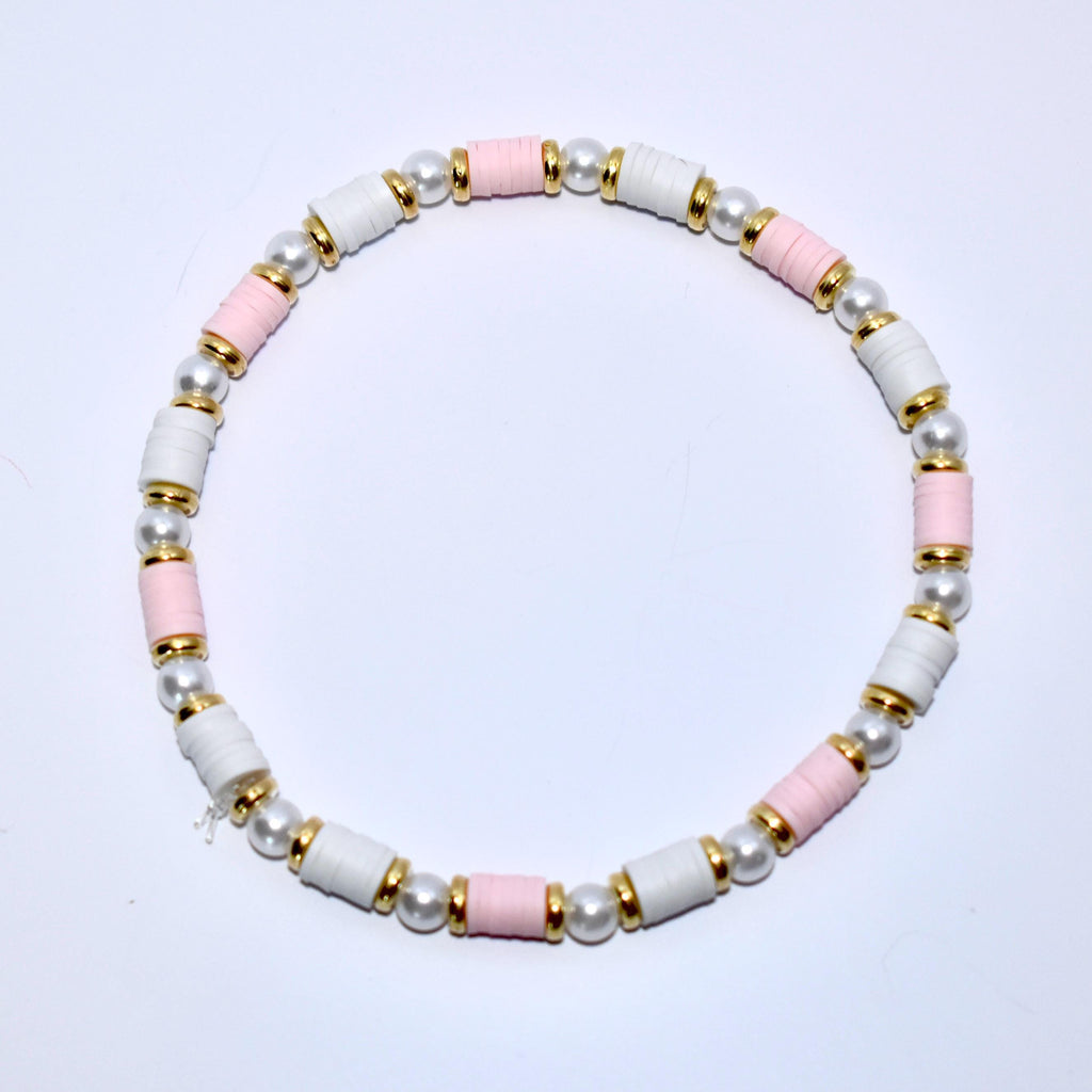 A pink and white beaded bracelet with gold accents. The bracelet is made of small, round beads and has a simple design.