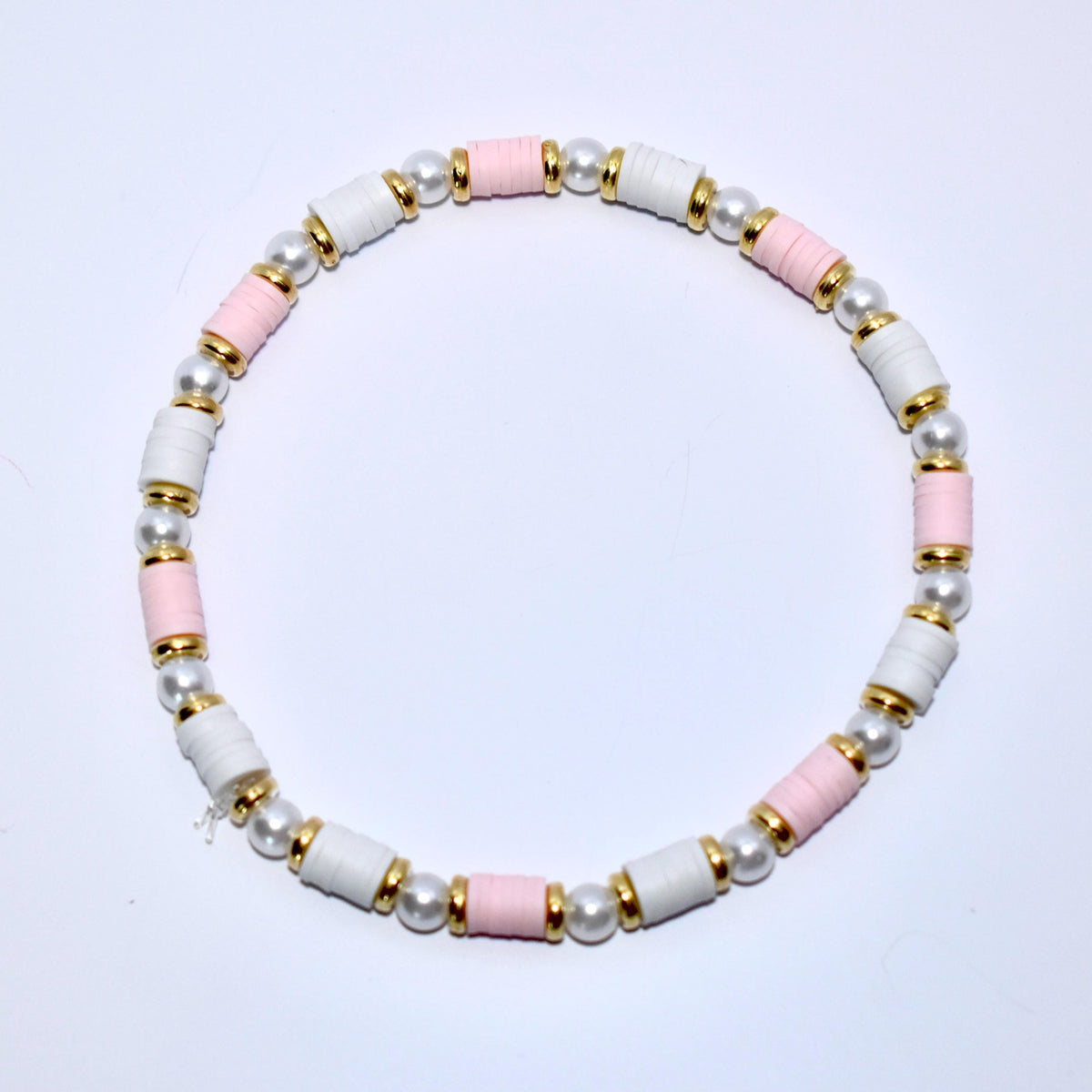 A pink and white beaded bracelet with gold accents. The bracelet is made of small, round beads and has a simple design.