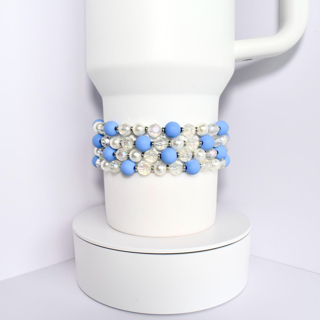 A white Stanley with a blue and white beaded wrap. The beads are alternating colors and are made of a smooth material.