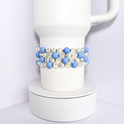 A white Stanley with a blue and white beaded wrap. The beads are alternating colors and are made of a smooth material.