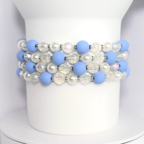 Four bracelets made of light blue and white beads. The bracelets feature alternating light blue matte beads and clear iridescent beads. The bracelet also includes white pearl beads.