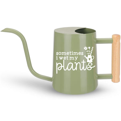 A sage green metal watering can with a wooden handle. The watering can has a white inscription that reads 'sometimes i wet my plants' with a small flower and watering can graphic.
