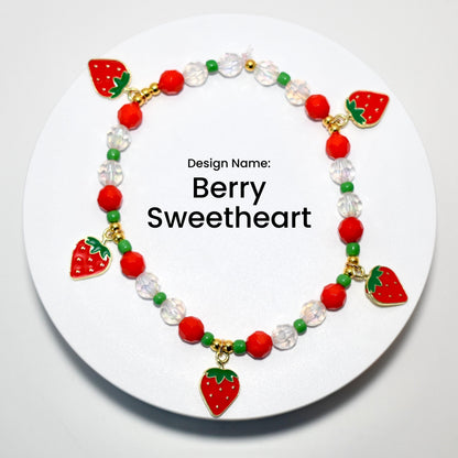 A red and green beaded bracelet with strawberry charms. The bracelet has a white background with the text 'Design Name: Berry Sweetheart'.
