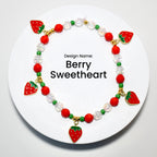 A red and green beaded bracelet with strawberry charms. The bracelet has a white background with the text 'Design Name: Berry Sweetheart'.