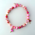 A pink beaded bracelet with three pink flamingo charms. The bracelet is made with pink and gold beads.